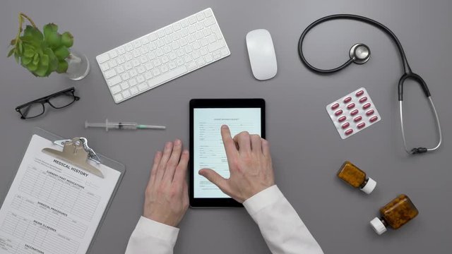 Top View Of Doctor Examining Patient Information Form On Digital Tablet