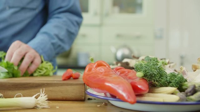 Vegetables In Plate By Man Cutting Cilantro On Chopping Board