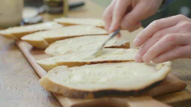 Closeup Of Man's Hands Spreading Butter On Bread Slice