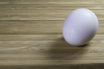 one fresh white egg on a bamboo cutting board background