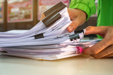 Businessman hands working in Stacks of paper files for searching information on work desk office, business report papers,piles of unfinished documents achieves with clips indoor,Business concept