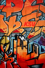 A fragment of detailed graffiti of a drawing made with aerosol paints on a wall of concrete tiles. Background image of street art in warm red color tones
