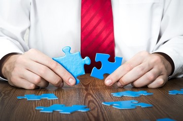 Closeup of a Businessman Combining Puzzle Pieces Together