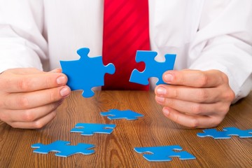 Closeup of a Businessman Combining Puzzle Pieces Together
