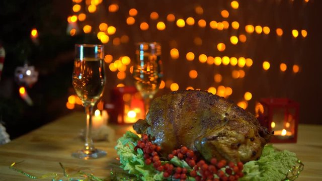 A roasted bird on a platter with a salad next to a glass of champagne stands on a table amidst yellow electric lights with a festive dinner in the evenings.