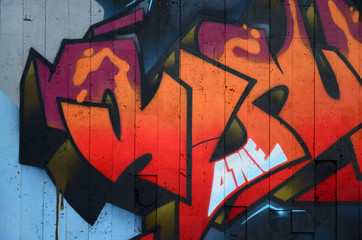 A fragment of detailed graffiti of a drawing made with aerosol paints on a wall of concrete tiles....