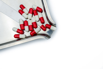 Red, white antibiotic capsules pills with shadow on stainless steel drug tray. Drug resistance, antibiotic drug use with reasonable, health policy and health insurance concept.