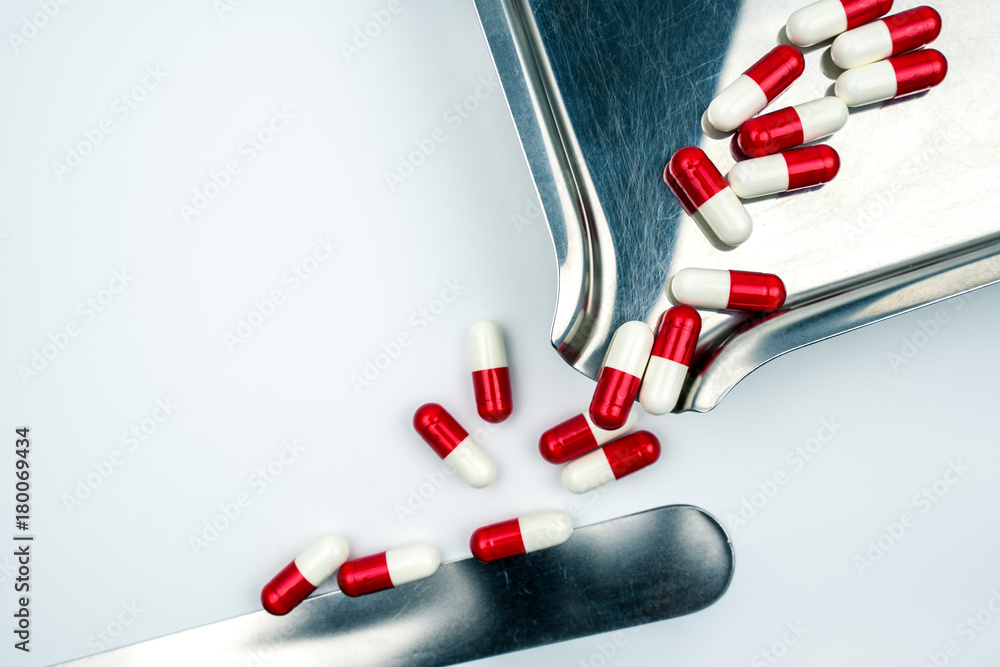 Wall mural Red, white antibiotic capsules pills with shadow on stainless steel drug tray. Drug resistance, antibiotic drug use with reasonable, health policy and health insurance concept.