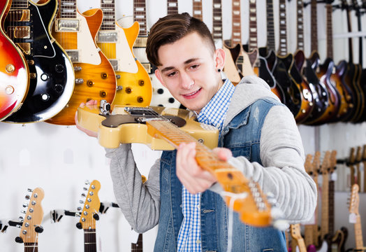 Male teenager examining electric guitars