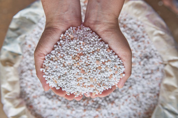  close up woman farmer hand hold chemical Fertilizer over sacks