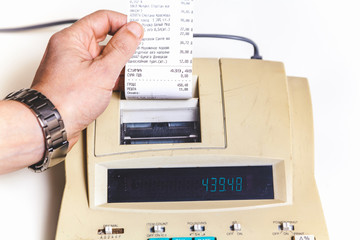 Hand removes check from printing calculator on white background