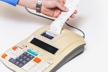 Hand removes check from printing calculator on white background