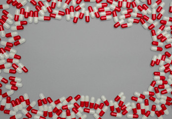 Red, white antibiotic capsules pills on grey background with copy space. Drug resistance, antibiotic drug use with reasonable, health policy and health insurance concept.