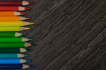 Line of colored pencils on wooden table