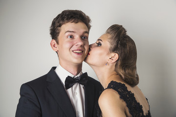 Elegant girl kisses a happy young man on the cheek