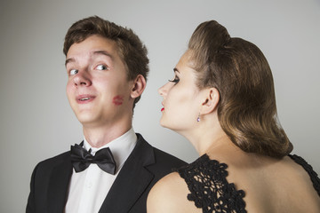 Elegant girl kisses a happy young man on the cheek