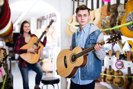 Teenagers examining guitars in shop