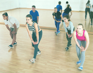 Fototapeta na wymiar Teenage boys and girls with trainer stretching in dance hall