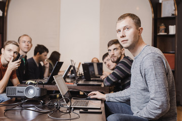 Coworkers in classroom watching presentation with projector while working together. 