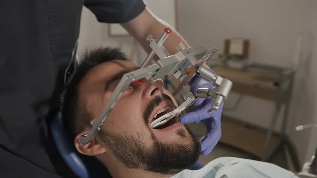 The orthodontist applies a face boy to his patient to achieve a more successful cosmetic effect during the treatment of teeth