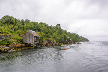 Serene Scandinavian Fjord Panorama fishing village with fishing boats, blue sky and puffy clouds in...