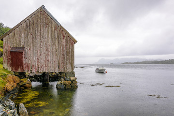 Serene Scandinavian Fjord Panorama fishing village with fishing boats, blue sky and puffy clouds in...