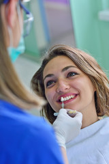 people, medicine, stomatology and health care concept - happy female dentist checking patient girl teeth