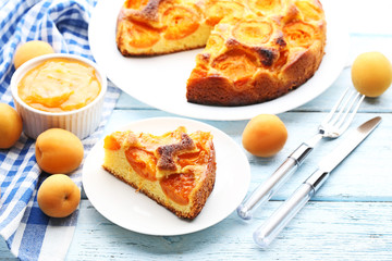 Slice of apricot pie with jam on blue wooden table
