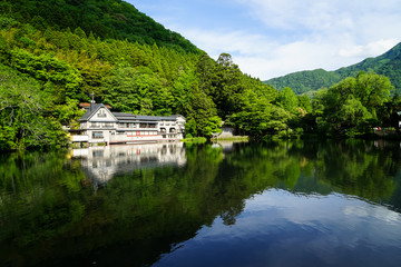 Beautiful abundant natural green mountain landscape symmetrical reflection on fresh lake Kinrin with buildings during springtime