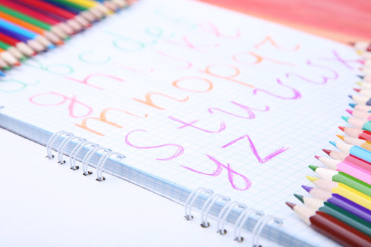 Handwritten alphabet in notebook with colorful pencils