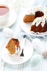 Bundt cake with sprinkles and easter eggs on wooden table