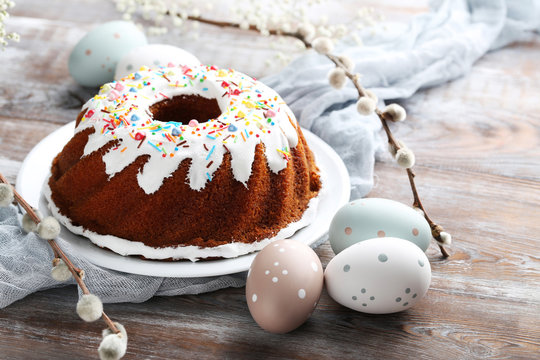 Bundt cake with sprinkles and easter eggs on wooden table
