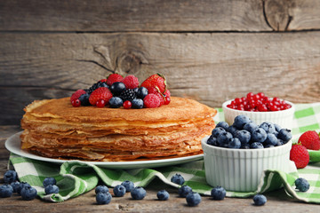 Pancakes with berries on grey wooden table