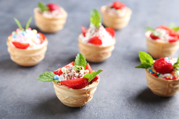 Dessert tartlets with strawberries on grey wooden table