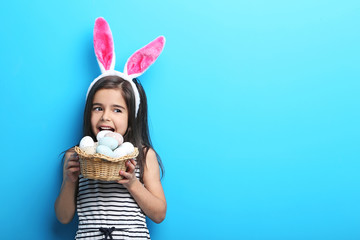 Beautiful little girl with rabbit ears and easter eggs on blue background