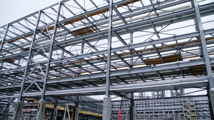 Scaffolding installation at a tank with process structures of refinery petrochemical plants in the background. Large steel structures for plant