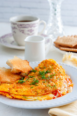 Breakfast with an omelette with tomatoes and cheese, tea and biscuits, selective focus