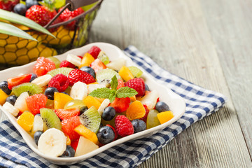 Delicious fruit salad with fresh fruit. Wooden, gray table in the background.