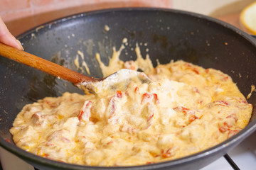 Preparation of cutted paprika with chicken meat and cheese in black frying pan