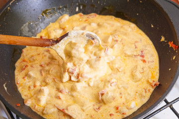 Preparation of cutted paprika with chicken meat and cheese in black frying pan