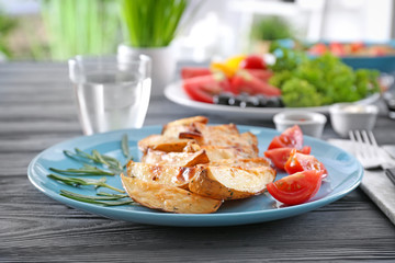 Plate with delicious baked rosemary potatoes on wooden table