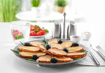 Plate with delicious baked rosemary potatoes on table