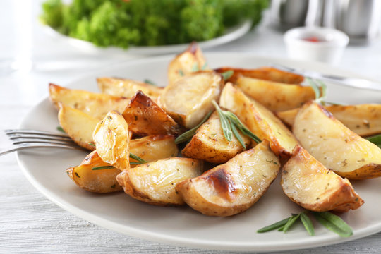 Plate with delicious rosemary potatoes on table
