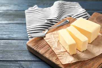 Rolgordijnen Cut block of butter on wooden board © Africa Studio