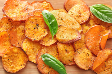 Yummy sweet potato chips on wooden background