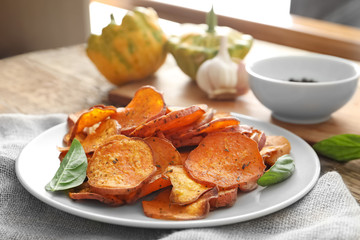 Plate with yummy sweet potato chips on table
