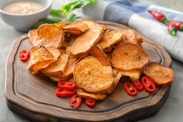 Yummy sweet potato chips on wooden board