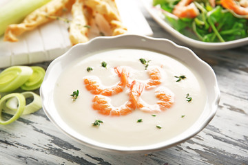 Tasty cream soup with fresh shrimps in bowl on table
