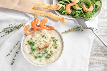 Tasty cream soup with fresh shrimps in bowl on table