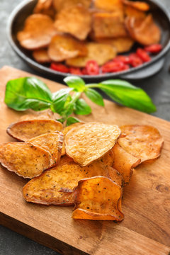 Yummy sweet potato chips on wooden board, closeup